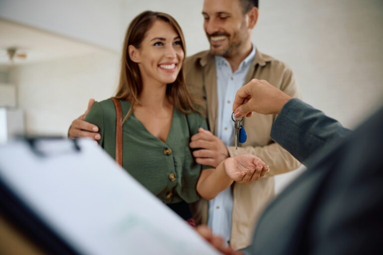 Happy couple receiving keys of their new home from real estate agent.