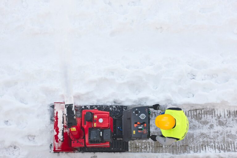 Worker cleaning snow on the sidewalk with a snowblower. Maintenance