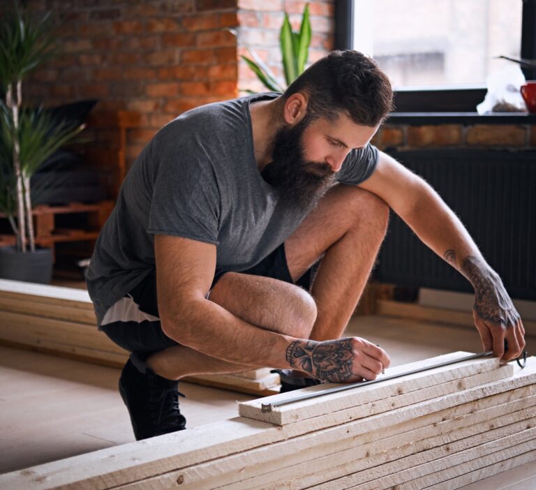 Carpenter measuring boards in a room with loft interior.