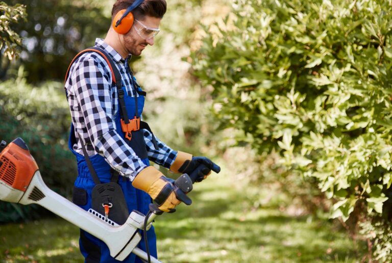 Gardener with weedwacker cutting the grass