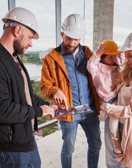 Family choosing interior design with builder at construction site.