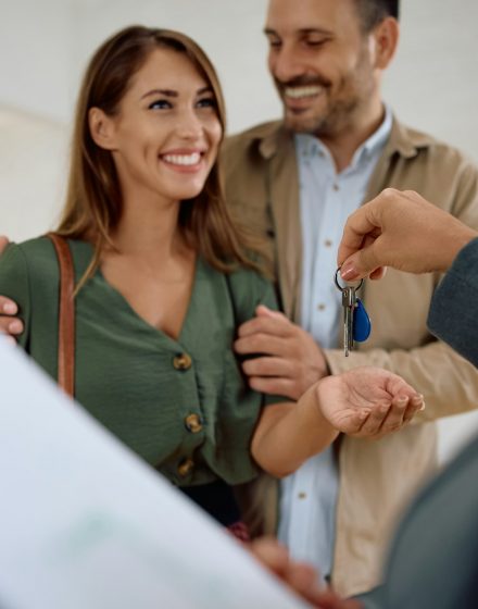 Happy couple receiving keys of their new home from real estate agent.