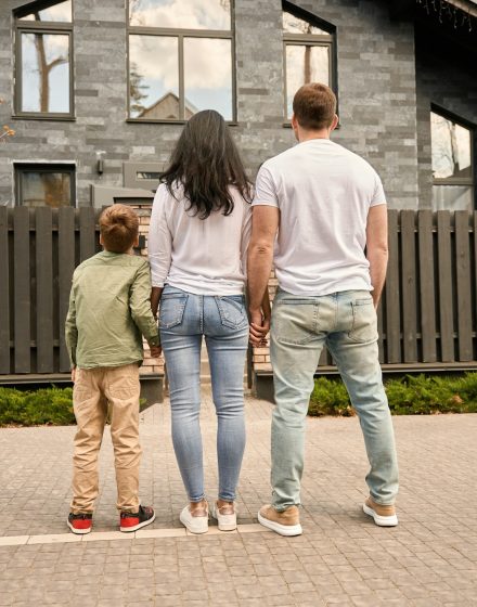 Young family stands and looks at their house