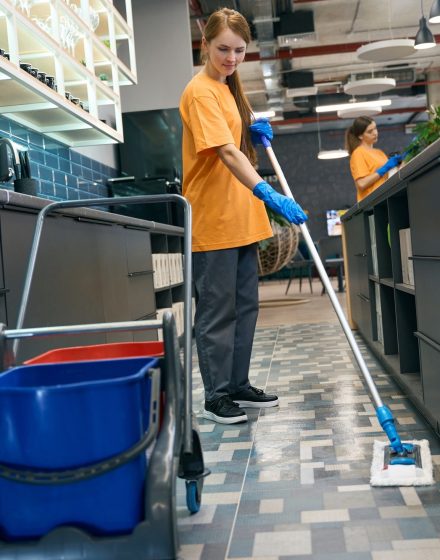 Young woman cleaning the floor with a mop