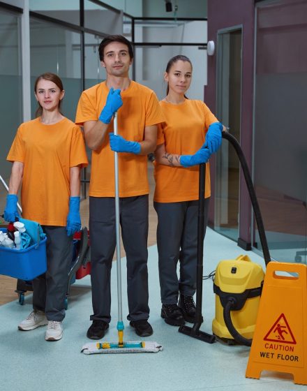 Young workers of cleaning company standing together with tools